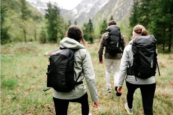 Shot van de wandelrugzakken van drie wandelaars in een sportieve look van achteren