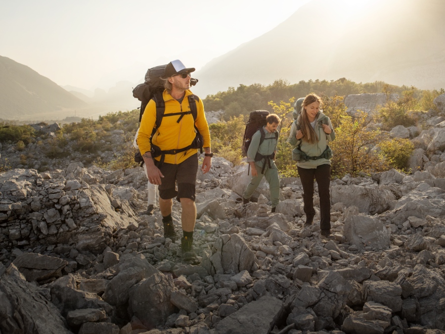 Drie wandelaars met trekkinguitrusting in de bergen